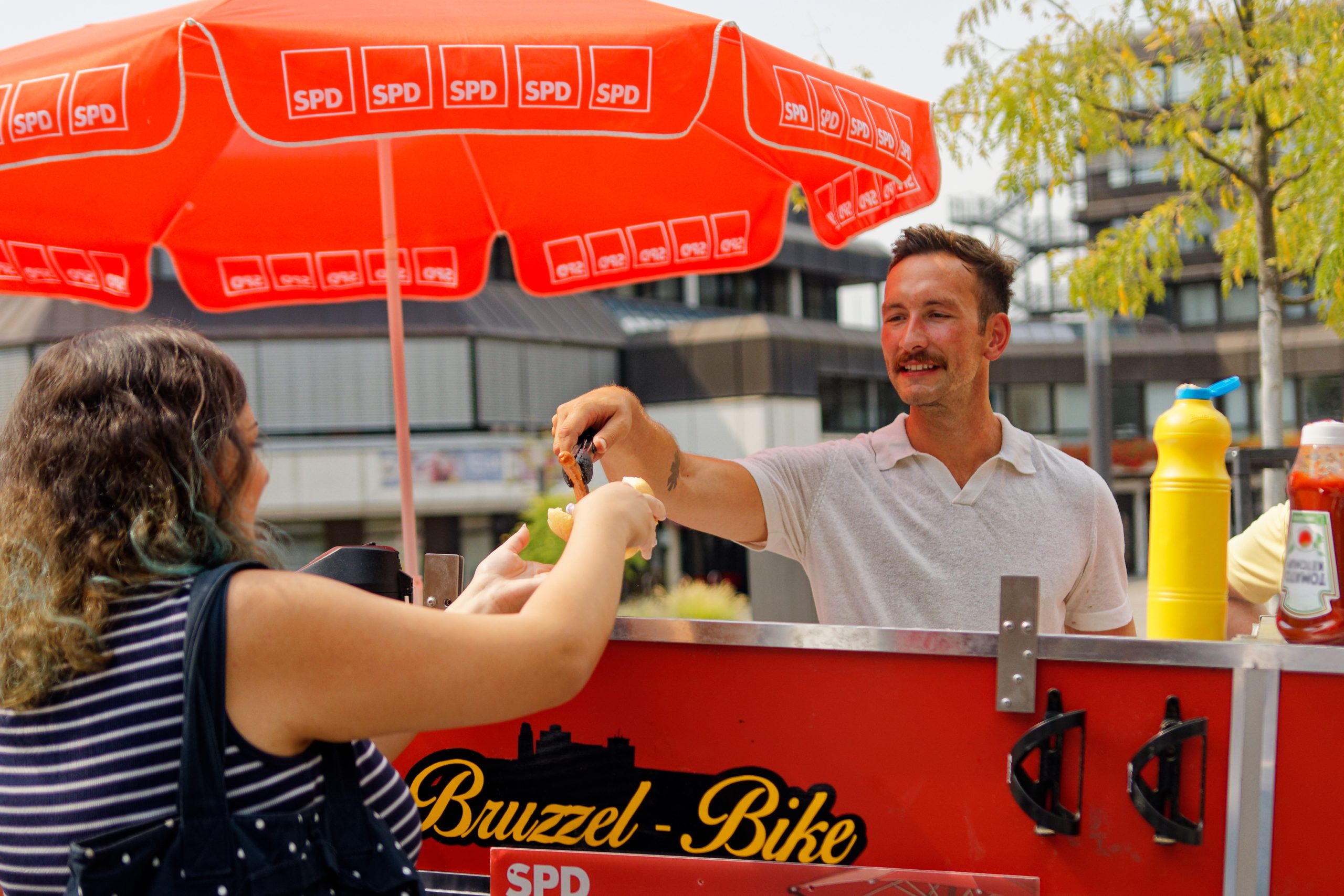 Simon Skibitzki (SPD) überreicht eine frisch gebratene Wurst
