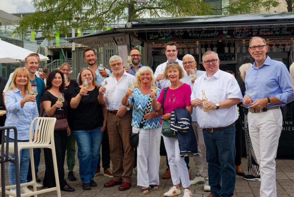 Eine Gruppe an Menschen eröffnet das Weinfest in Sankt Augustin mit erhobenen Gläsern